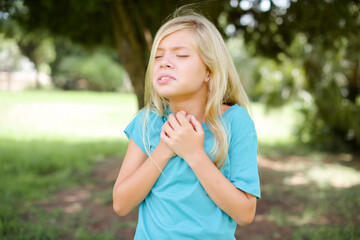 Sad Caucasian little kid girl wearing blue T-shirt standing outdoors desperate and depressed with tears on her eyes suffering pain and depression  in sadness facial expression and emotion concept