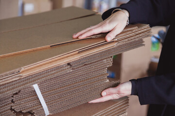 Woman taking folded stacks of corrugated cardboards for packing in warehouse