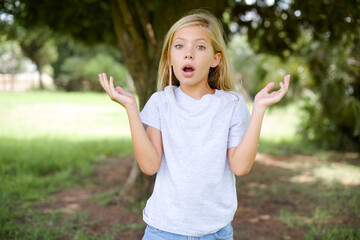 Surprised terrified Caucasian little kid girl wearing white T-shirt standing Gestures with...