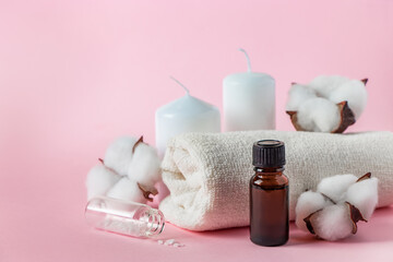Obraz na płótnie Canvas Natural cosmetic products for spa and aromatherapy. Relaxation concept. Candles, flowers and a towel on a pink background.