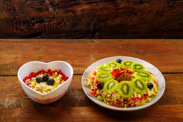 Chicken breast puff salad garnished with kiwi and olives and pineapple salad in a salad bowl on the table.