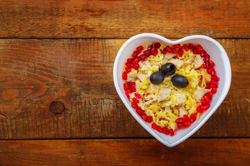 Puff salad with pineapple in a salad bowl decorated with pomegranate on the table.