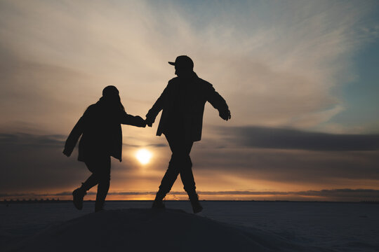 Silhouettes of a man and a woman in love against the background of a winter sunset