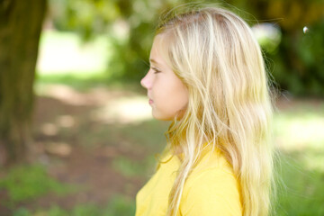 Fototapeta premium Profile portrait of nice beautiful Caucasian little kid girl wearing yellow T-shirt standing outdoors look empty space toothy smile