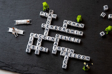 Fototapeta na wymiar the team of miniature figurines of special doctor forces, seting up a crossword puzle with covid keywords, is covid vaccine really safe? black background