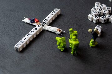 miniature cubic letters  and miniature figurines laying on a stretchers forming a cross a crucifix...