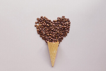 Coffee love concept. Roasted coffee beans in shape of heart in waffle cone for ice cream
