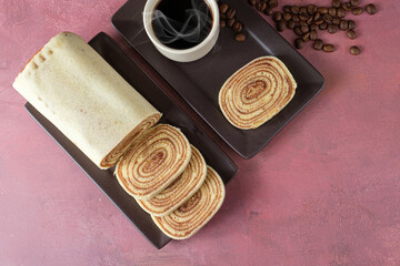 Sliced bolo de rolo (roll cake) next to cup and coffee beans.