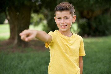 Caucasian little kid boy wearing yellow T-shirt standing outdoor  pointing displeased and frustrated to the camera, angry and furious ready to fight with you.