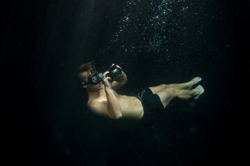 Plakat young man taking underwater pictures doing free dive