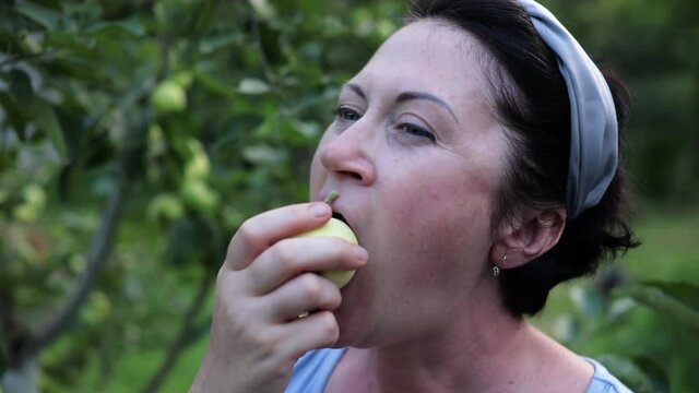 40s woman pick apple from tree- bite chew fruit 