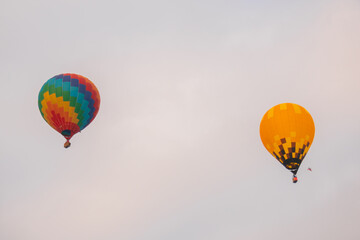 Two colorful hot air balloons flying against grey sky at Winter aerostat festival. Freedom, sport, aircraft concept