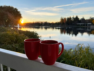 Obraz premium Coffee cup with beautiful sunrise and lake in the background.