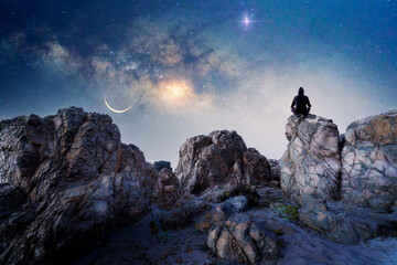 Naklejka na ściany i meble person on the rock outdoors meditating or praying at night under the Milky Way