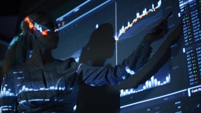 Business Conference Meeting Presentation: Businesswoman does Financial Analysis talks to Group of Businessspeople. Projector Screen Shows Stock Market Data, Investment Strategy, Revenue Growth
