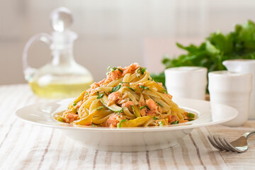 Italian dinner. Linguine pasta with salmon and zucchini on a table.