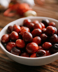 Bowl of cranberries on brown wooden table. 