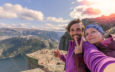 A cheerful couple in the summit of the Pulpit Rock (Preikestolen), one of the world's most...