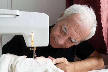 old male man senior sit next at table at home work, sewing machine enjoy
