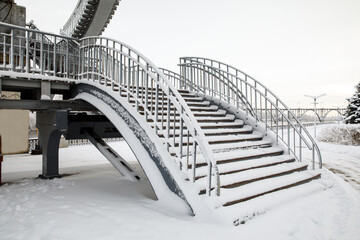 Staircase with metal railings for climbing the bridge, covered with snow in winter. Element of architecture, design on a city street. Dnipro city in winter, Dnipropetrovsk , Ukraine