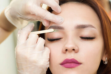 A makeup artist does a facial hair removal procedure. Professional makeup. The master applies hot...