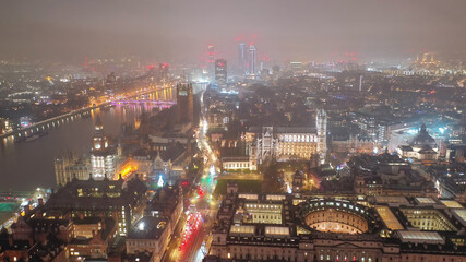 Aerial drone night shot of iconic City of Westminster with houses of Parliament, Big Ben in front of river Thames, London, United Kingdom