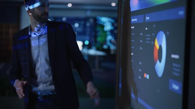 Conference Business Meeting Presentation: CEO Businessman Shows Data to Group of Investors, Businessspeople. Projector Screen Shows Graphs, Product Sales, Revenue Growth Strategy, e-Commerce Analysis