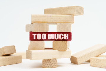 On the white surface there is a ruined tower made of planks, on a red plaque there is an inscription - Too Much