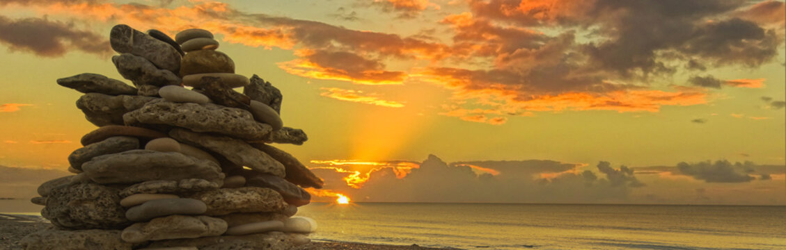 Empilement de galets sur une plage au coucher de soleil, ambiance zen.