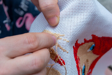 Women's hand embroidery in a hoop, a woman embroider a pattern on dark material. Close-up. The...