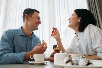 Portrait of happy guy and girl at home in kitchen. Morning breakfast for couple. Kind, sparkling emotions. Home comfort.