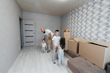 A young father with children brings a box of things after moving to a new apartment. Purchase of real estate. Housewarming, delivery and transportation of goods.