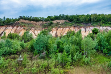 Fototapeta na wymiar Colorful clay hills overgrown with green trees. Natural abstract landscape, aerial view from drone