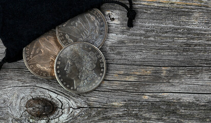 Small bag of US Morgan silver dollars with patina finish on weathered wooden table