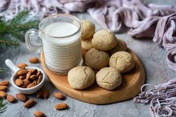Delicious dessert for breakfast: almond cookies on a wooden board and a cup of milk on a gray background. Close-up