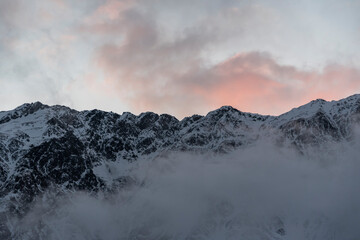 Beautiful winter mountains landscape on the sunrise. High snow covered mountains in the fog. Georgia, Kazbegi.