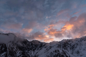 Beautiful winter mountains landscape on the sunrise. High snow covered mountains in the fog. Georgia, Kazbegi.