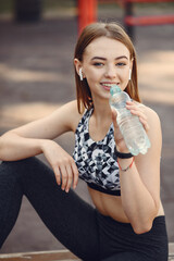 Sports girl in a black top training in a summer park