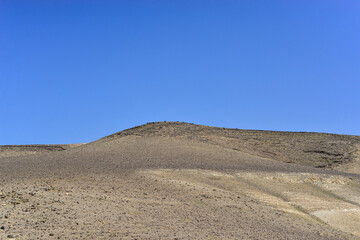 Fototapeta na wymiar Stone Desert on the West Bank. Judean Desert in clear weather. White sand dunes and blue sky. Stony desert in the spring, green grass. Sand Hills of Judean Mountain, Israel. 