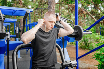 Young Man exercising in the street on a press deck machine for press and press muscles workout.