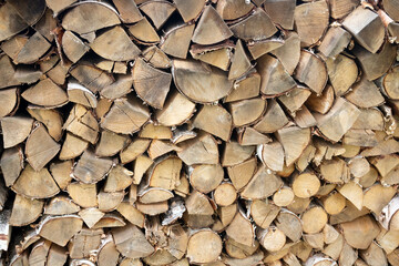 A beautiful closeup view of cut and split firewood stacked outdoor up against a shed under roof