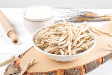 Whole grain wheat raw apulian pasta called Pizzarieddi or maccaruni on a ceramic plate on white...