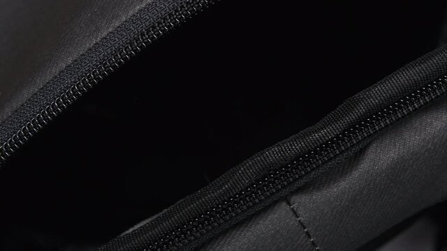 A Man's Hand Zips And Unzips A Black Travel Backpack With A Zipper. Close-up Of The Zipper Of The Travel Bag. Open And Close The Zipper Of The Bag Top View. Macro Shot