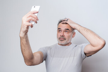 A man in a T-shirt takes a selfie on a mobile phone