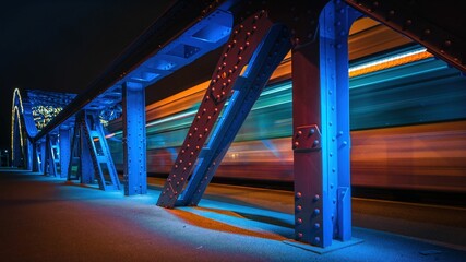 Rozpędzony tramwaj przejeżdżający przez stalowy most - obrazy, fototapety, plakaty