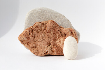 Multi-colored grey and red stones on a white background. Natural podium