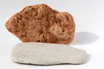 Multi-colored grey and red stones on a white background. Natural podium