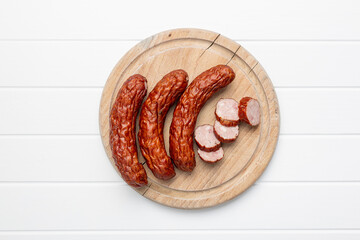 Smoked pork sausages on cutting board. Sliced salami on white table.