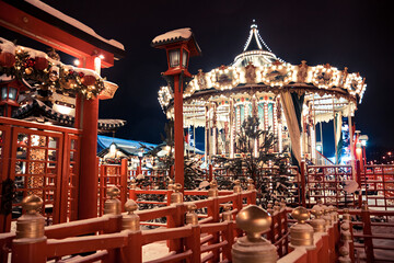 Night winter scene of Chinese New Year celebration with details of Chinese architecture and European carousel 