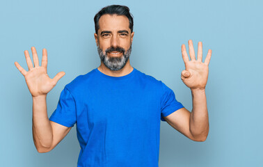 Fototapeta premium Middle aged man with beard wearing casual blue t shirt showing and pointing up with fingers number nine while smiling confident and happy.